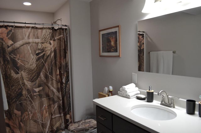 bathroom with walk in shower, vanity, and toilet