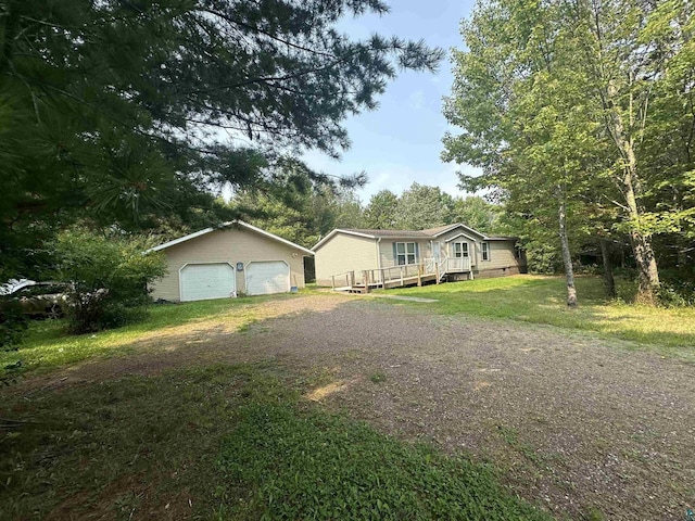 view of front of home featuring a garage, crawl space, a front lawn, and an outbuilding