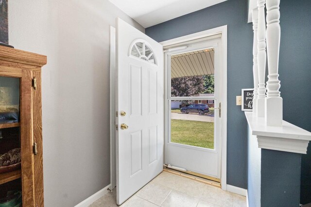 foyer entrance with light tile patterned floors and baseboards