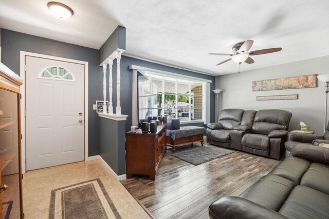 living room with a ceiling fan, decorative columns, baseboards, and wood finished floors