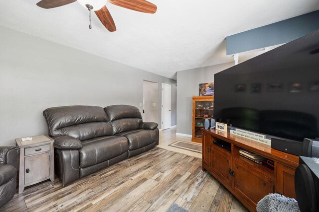 living room featuring light wood finished floors, a ceiling fan, and baseboards