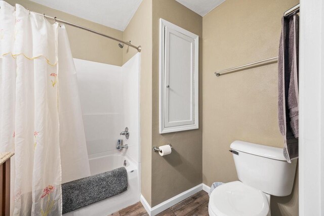 bathroom featuring toilet, baseboards, shower / bath combo with shower curtain, and wood finished floors