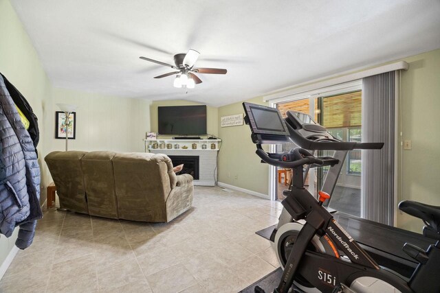 exercise area featuring a brick fireplace, ceiling fan, and baseboards