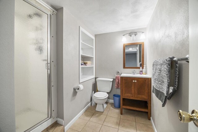 bathroom with tile patterned flooring, toilet, a shower stall, and baseboards