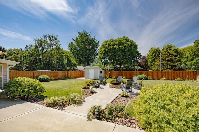 view of yard with a storage shed, an outdoor fire pit, a patio, a fenced backyard, and an outdoor structure