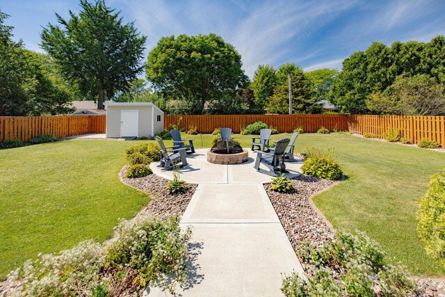 view of yard featuring a patio, a shed, a fenced backyard, an outdoor structure, and a fire pit