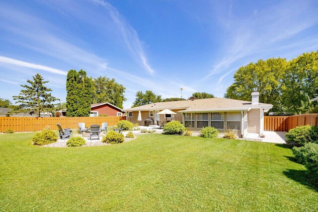 rear view of property with a sunroom, fence, a lawn, and a patio