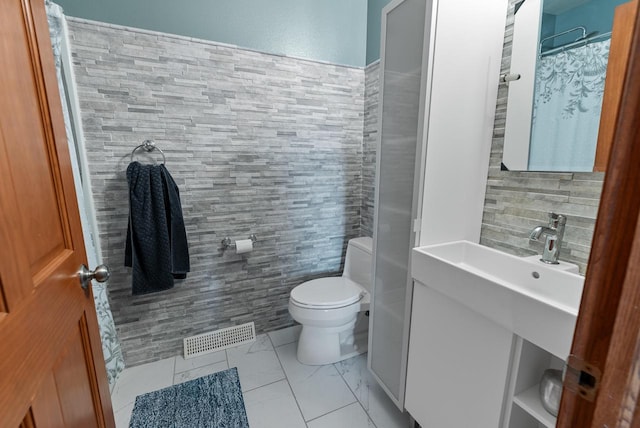 bathroom with vanity, toilet, a shower with curtain, and tile walls