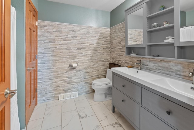 bathroom featuring vanity, toilet, tile walls, and decorative backsplash