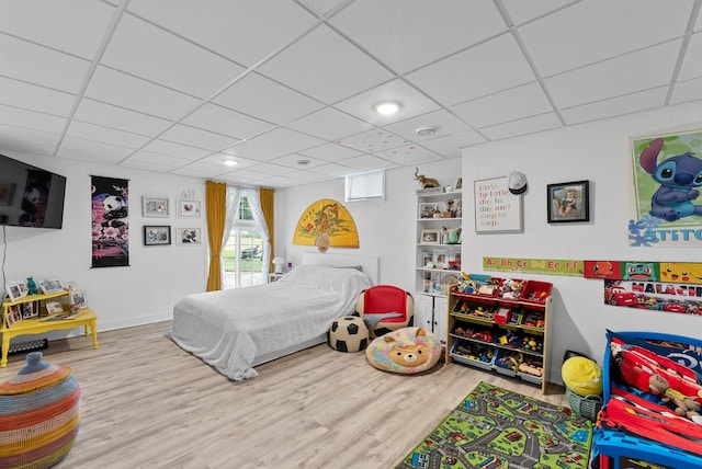 bedroom with a paneled ceiling and light hardwood / wood-style floors