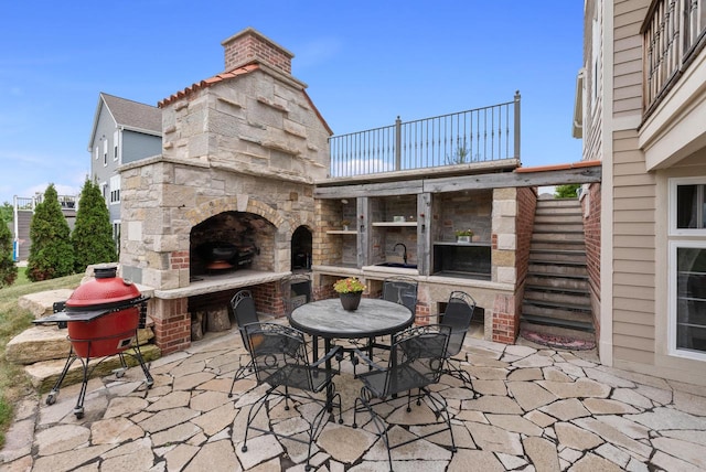 view of patio / terrace with an outdoor stone fireplace and sink