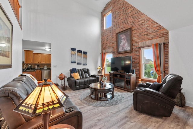 living room featuring light wood-type flooring, high vaulted ceiling, and sink