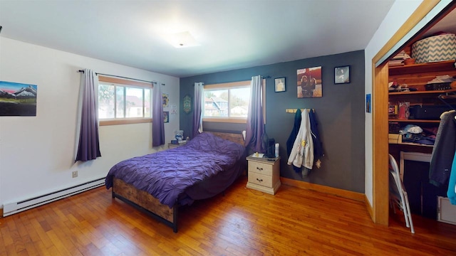 bedroom featuring a closet, a baseboard radiator, and wood-type flooring