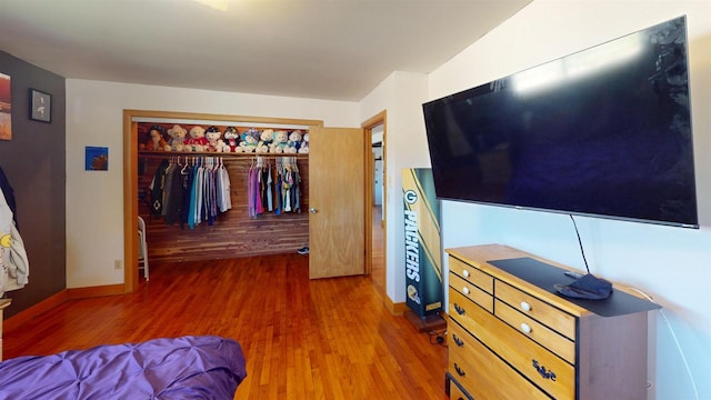 bedroom with dark hardwood / wood-style flooring and a closet