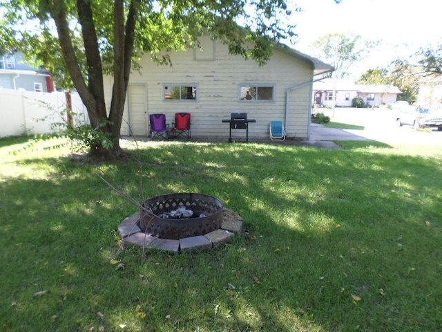 rear view of house with an outdoor fire pit and a lawn