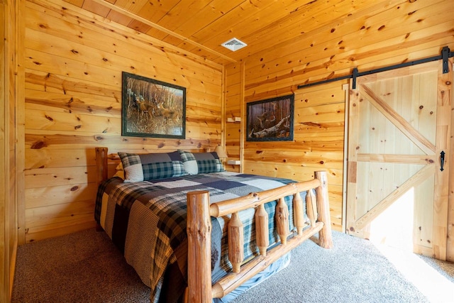 carpeted bedroom featuring a barn door, wood walls, and wooden ceiling