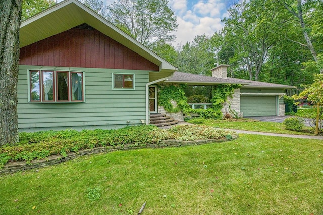 view of front of home with a front yard, a garage, driveway, and a chimney