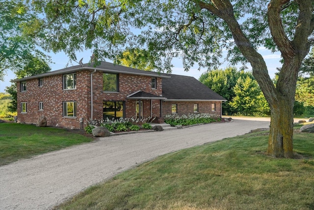 traditional-style house featuring driveway, brick siding, and a front yard