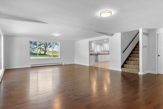 unfurnished living room with visible vents, stairway, baseboard heating, wood finished floors, and baseboards