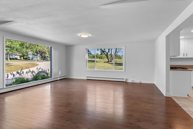 unfurnished living room with a baseboard heating unit, wood-type flooring, and baseboards