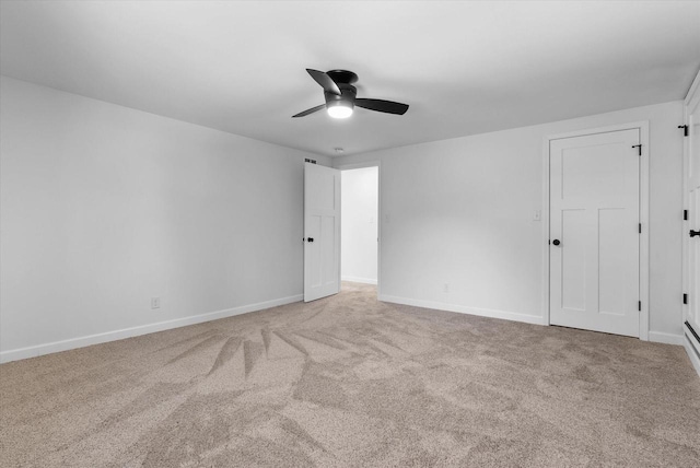 carpeted spare room with a ceiling fan and baseboards