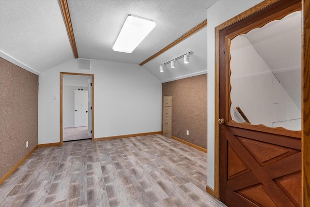 interior space featuring baseboards, a textured ceiling, visible vents, and light wood-style floors