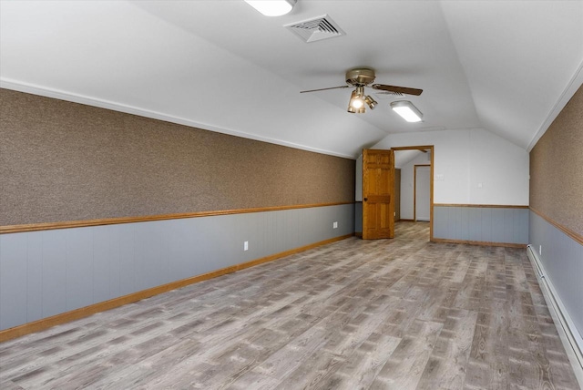 additional living space with lofted ceiling, visible vents, wainscoting, ceiling fan, and wood finished floors