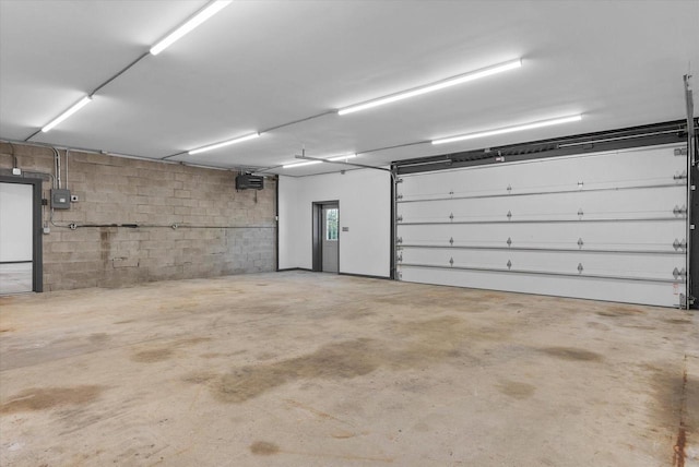 parking deck featuring concrete block wall, electric panel, and a garage door opener