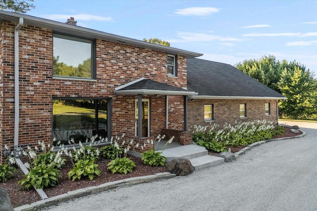 view of front of property featuring brick siding and a chimney