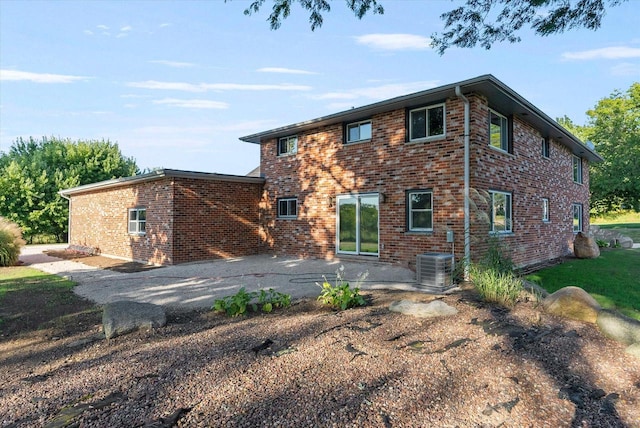 view of front facade with cooling unit, a patio area, and brick siding