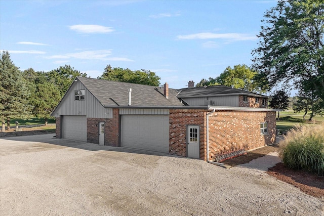 view of front of home with a garage, driveway, a chimney, and brick siding