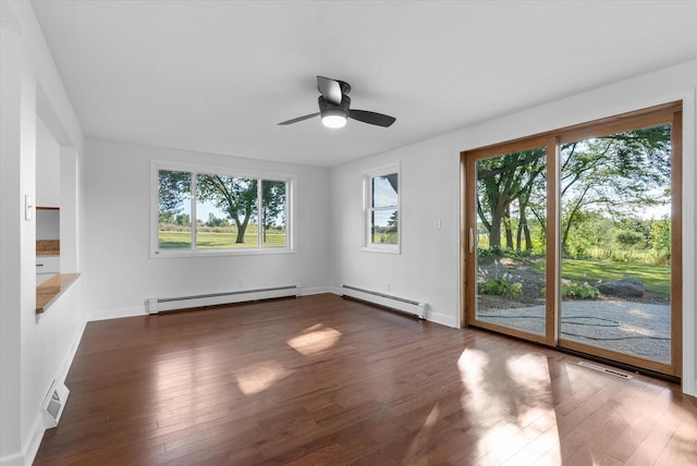 unfurnished room featuring a baseboard heating unit, dark wood finished floors, and baseboards