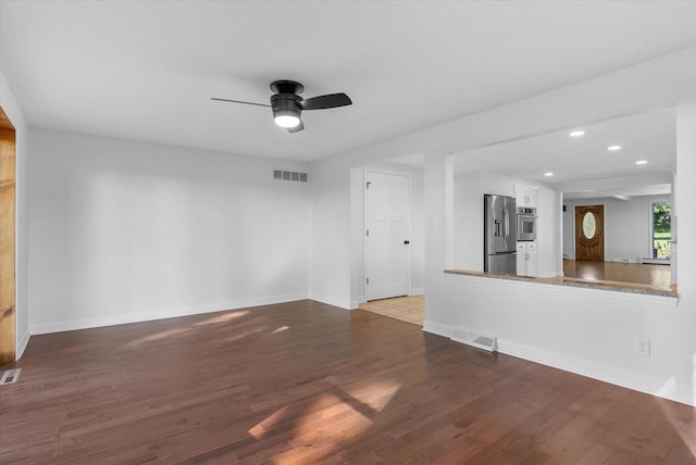 unfurnished living room featuring baseboards, visible vents, and wood finished floors