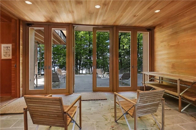 doorway to outside featuring french doors, wood ceiling, wood walls, and stone tile floors