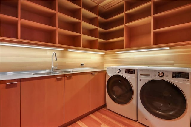 laundry area with a sink, cabinet space, separate washer and dryer, and light wood finished floors