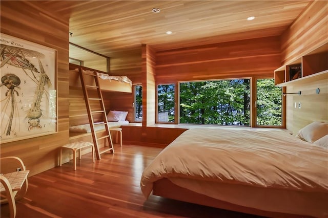 bedroom featuring wooden ceiling, multiple windows, wood finished floors, and wood walls