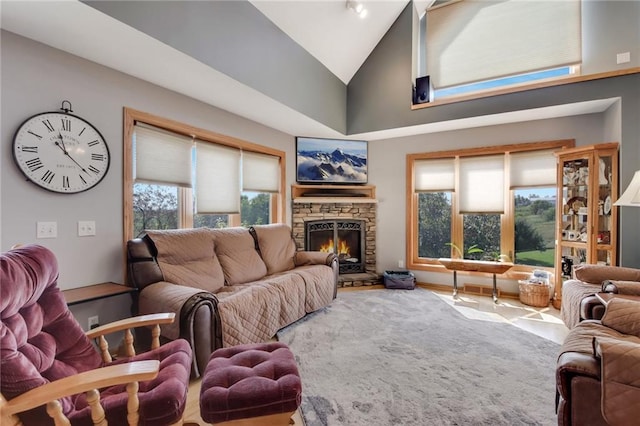 living room featuring a stone fireplace and high vaulted ceiling