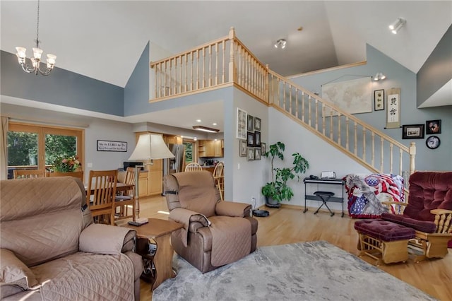 living room with light hardwood / wood-style flooring, high vaulted ceiling, and a chandelier