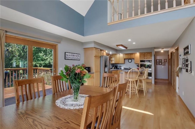 dining area featuring a skylight, light hardwood / wood-style flooring, and a high ceiling