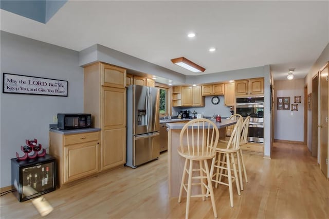 kitchen with a center island, light hardwood / wood-style flooring, stainless steel appliances, and a kitchen breakfast bar