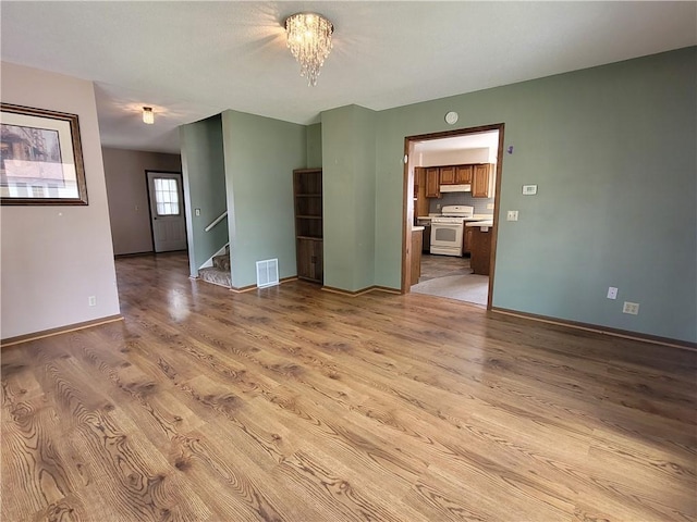 empty room with an inviting chandelier and light hardwood / wood-style floors