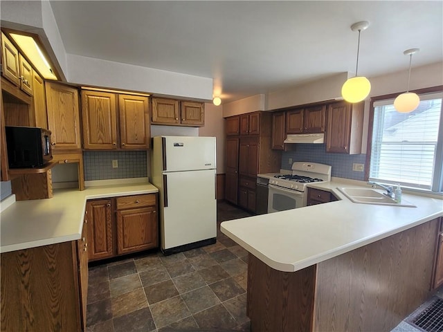 kitchen with white appliances, hanging light fixtures, kitchen peninsula, sink, and decorative backsplash