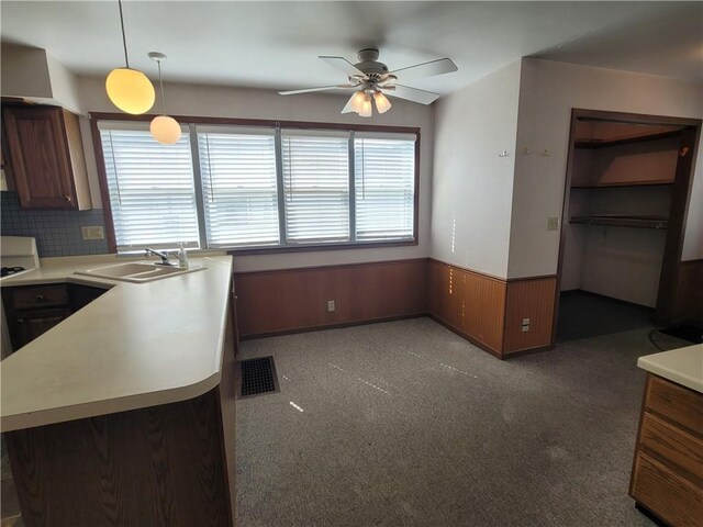 kitchen featuring decorative light fixtures, kitchen peninsula, sink, ceiling fan, and dark colored carpet