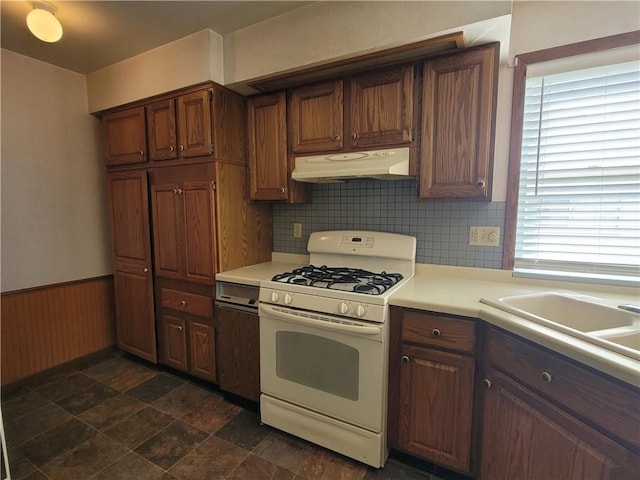 kitchen featuring white range with gas stovetop, decorative backsplash, and a healthy amount of sunlight