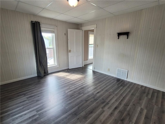 unfurnished room with dark wood-type flooring and a paneled ceiling