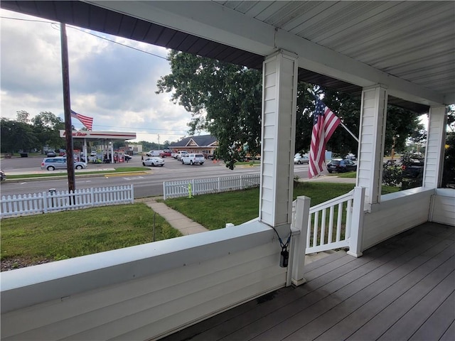 wooden terrace featuring a lawn and covered porch