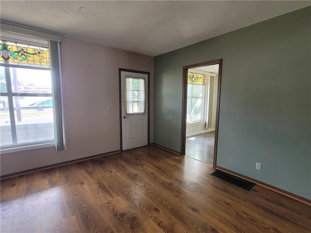 spare room with dark hardwood / wood-style flooring and a textured ceiling