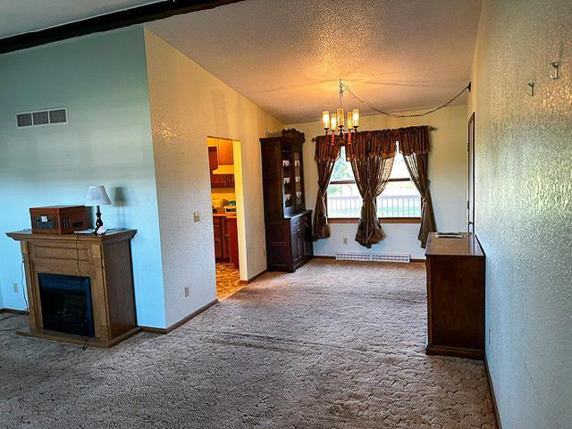 interior space with visible vents, carpet floors, lofted ceiling, a textured ceiling, and a chandelier