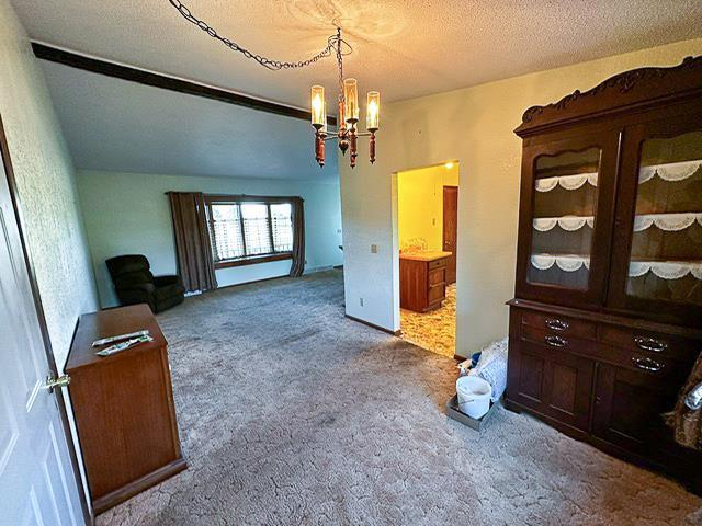 carpeted bedroom with a textured ceiling and an inviting chandelier