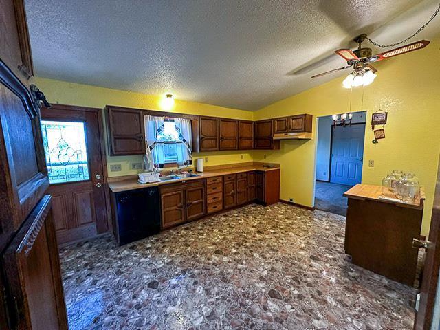 kitchen with ceiling fan, under cabinet range hood, dishwasher, lofted ceiling, and a textured ceiling